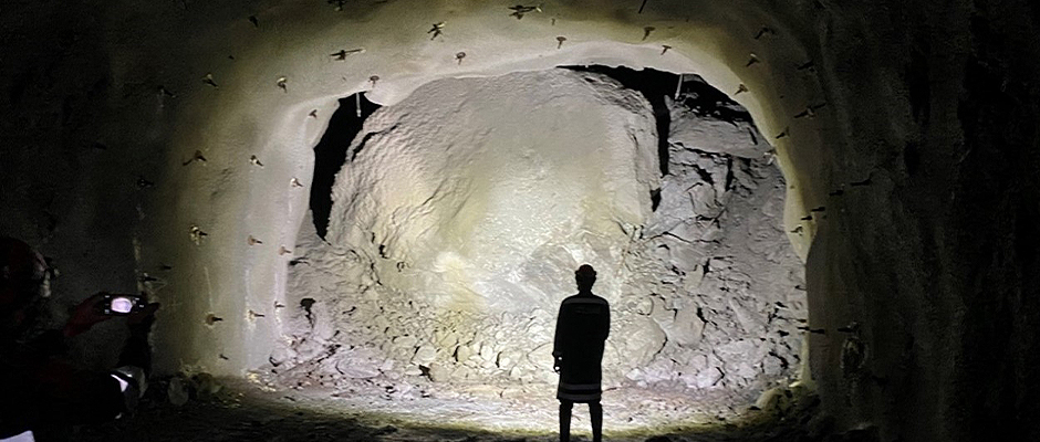 Person standing in cave with oversized boulder